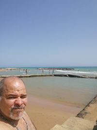 Portrait of man on beach against clear sky