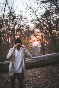 Man wearing sunglasses while standing in forest during sunset