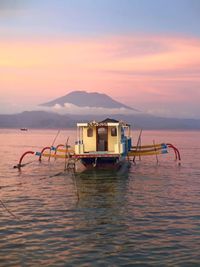 Boats in sea at sunset