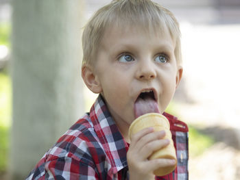 Cute boy licking ice cream in garden