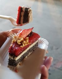 Close-up of hand holding cake slice in plate