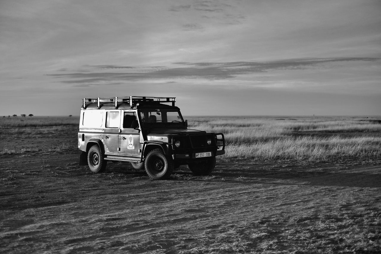 transportation, land vehicle, mode of transport, sky, car, cloud - sky, stationary, bicycle, travel, cloud, parking, parked, outdoors, landscape, road, day, beach, sand, field, nature