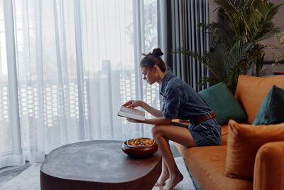 Side view of young man sitting on sofa at home