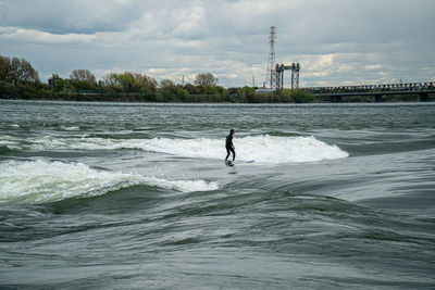 Man surfing in sea against sky