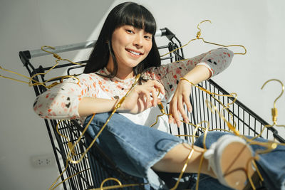 Portrait of young woman sitting in shopping cart