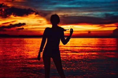 Silhouette man standing on beach during sunset