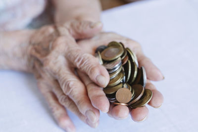 Wrinkled hands of senior woman holding coins