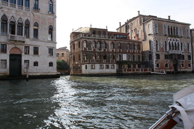 Canal by buildings against sky in city