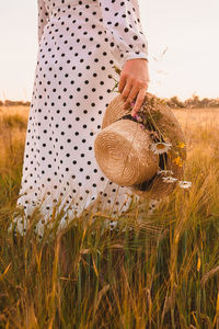 Midsection of woman holding basket on field