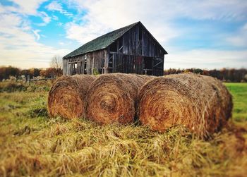 Hay bales in barn on field against sky