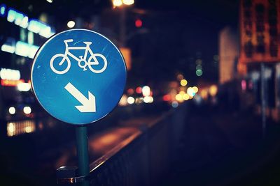 Bicycle sign by street in city at night