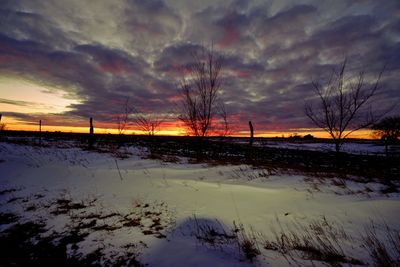 Scenic view of frozen landscape against sky at sunset