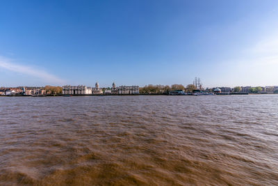 Scenic view of river by buildings against sky