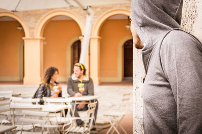 Rear view of people sitting in front of built structure