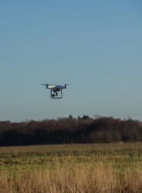 Drone flying over field against clear sky