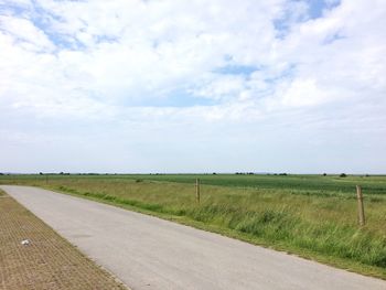 Scenic view of field and road against sky