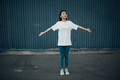 Full length portrait of a young woman standing in city