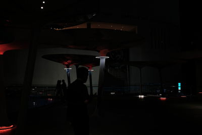 Silhouette man standing in illuminated city at night