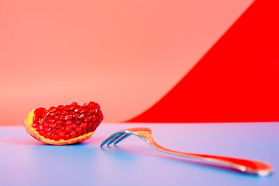 Pomegranate with fork on table against wall