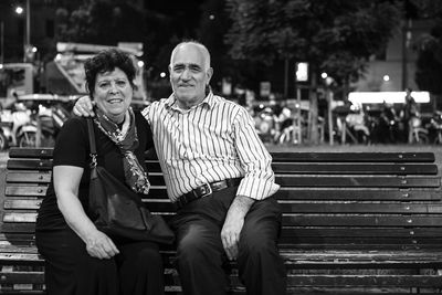 Portrait of senior couple sitting on bench at night