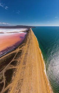 Aerial view of sand spit between clear azure sea and pink lake with salt