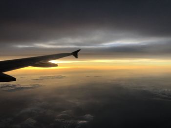 Airplane flying over cloudscape against sky during sunset