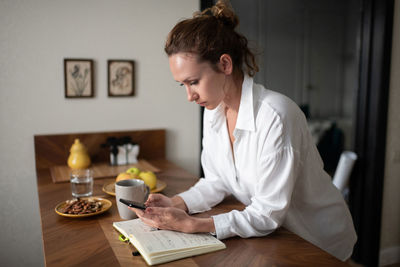 Female entrepreneur checking smartphone at home