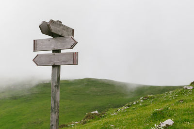 Blank information sign on field against sky