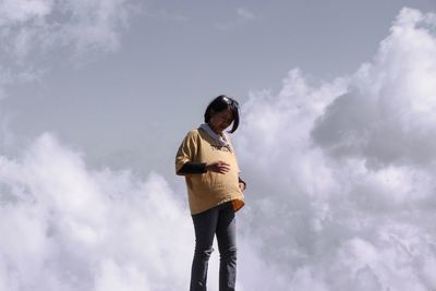 Low angle view of young man standing against sky