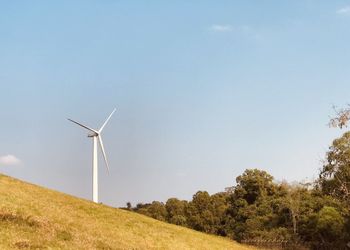 Wind turbines on field against clear sky