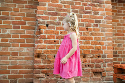 Young woman standing against brick wall