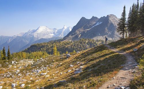 Man hiking by mountains against clear sky