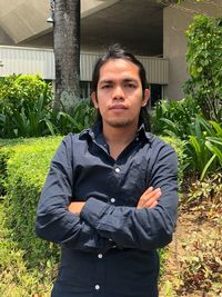 Portrait of young man standing against plants