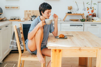 Portrait of young woman sitting on hardwood floor at home