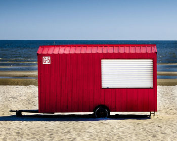 Red lifeguard hut on beach against clear sky