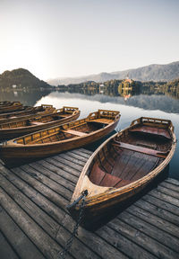 Boats on pier over lake against sky