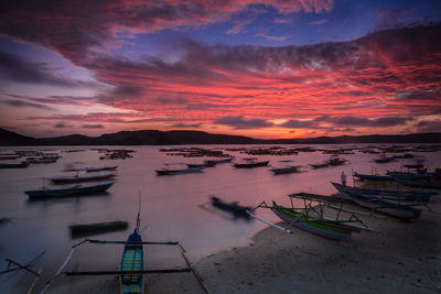 Boats moored in sea against sky during sunset