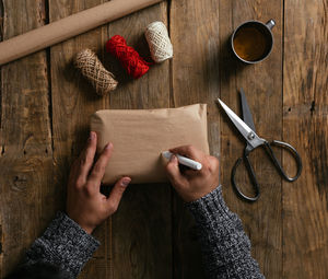 Top view of a man's hands packing a gift on a wooden table