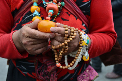 Midsection of woman with jewelry standing outdoors