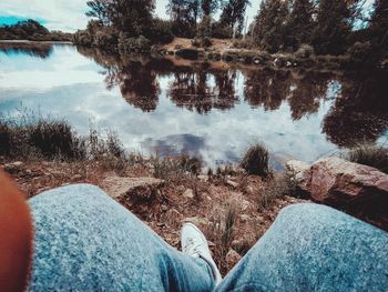 Low section of man on rock by lake