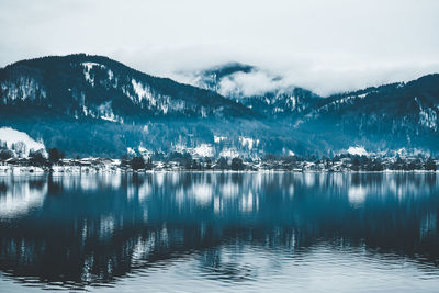 Scenic view of lake by snowcapped mountains against sky