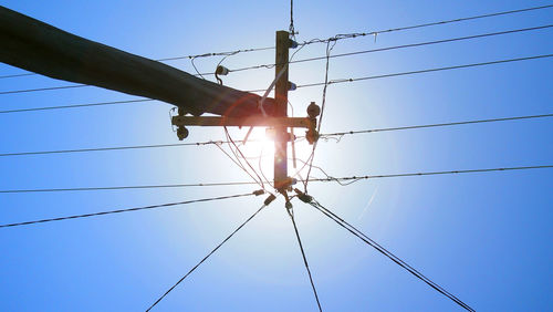 Low angle view of electricity pylon against blue sky