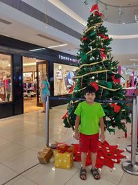 Full length of boy standing in illuminated christmas tree