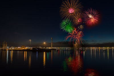 Firework display over river against sky at night