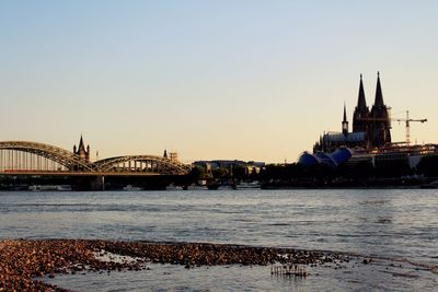 Hohenzollern bridge over rhine river by cologne cathedral against sky