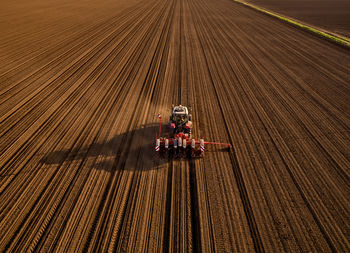 Serbia, vojvodina province, aerial view of tractor sowing seeds in plowed corn field