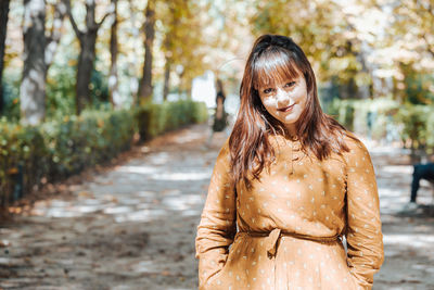 Portrait of young woman standing against trees