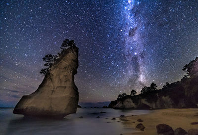 Rock formation in sea against sky at night