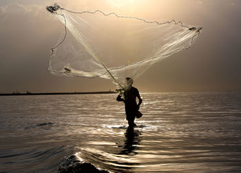 Silhouette man fishing in sea