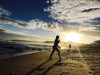 Silhouette man standing on beach against sky during sunset